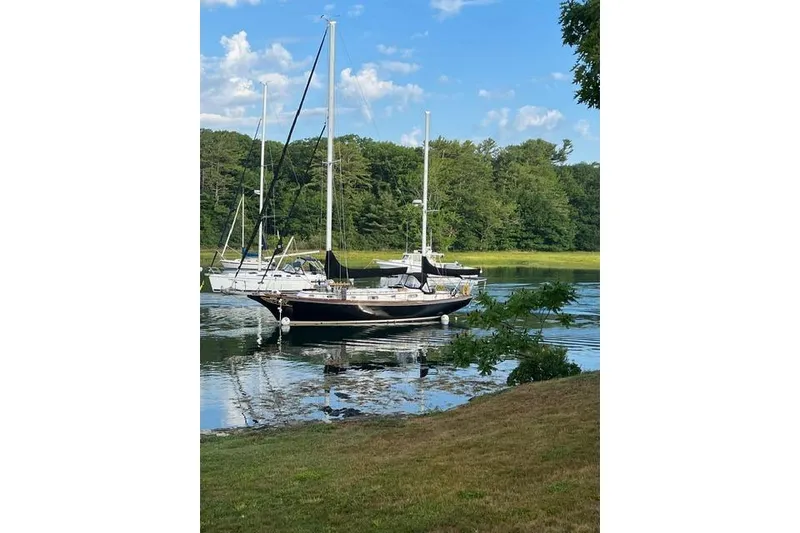 Slide: The Image of 1977 Fuji 45 MK II Ketch sailboat on calm water, surrounded by lush greenery. - 58