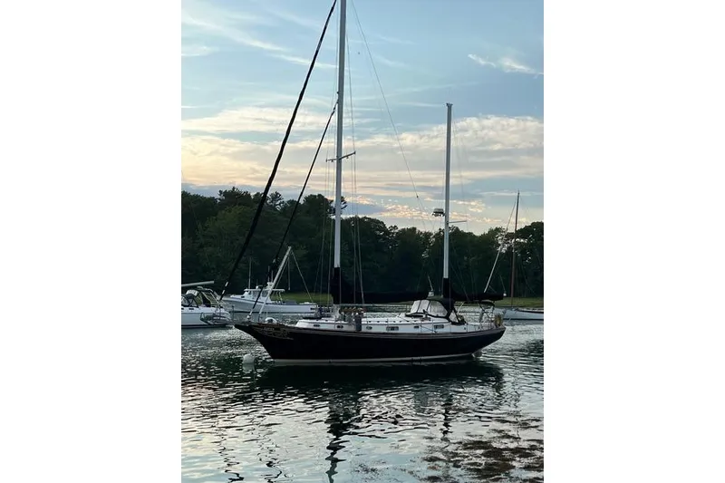 Slide: The Image of 1977 Fuji 45 MK II Ketch sailboat anchored on calm water at sunset. - 59