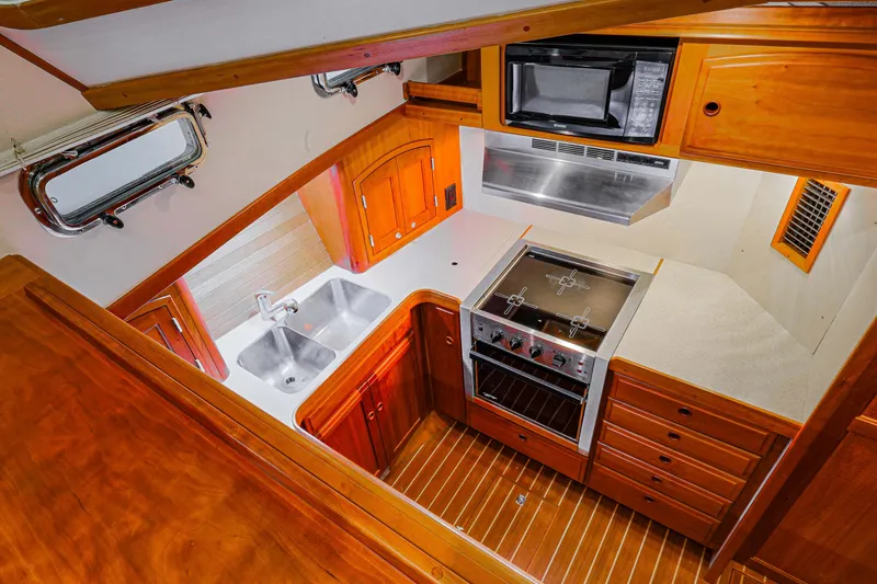 Slide: The Image of 2002 Sabreline 47 yacht kitchen with wood cabinetry, dual sink, stove, and microwave. - 4