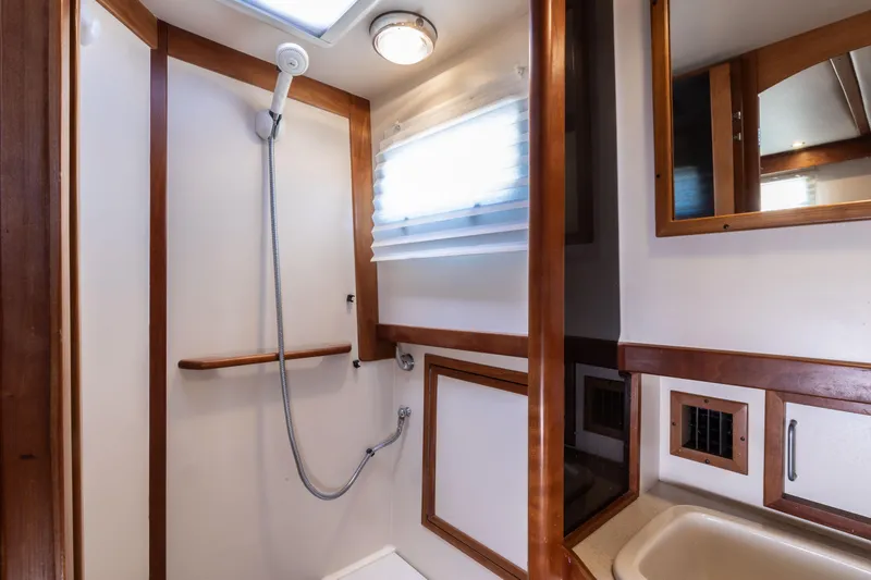Slide: The Image of 2002 Sabreline 47 yacht bathroom with shower, wooden accents, and mirror. - 11
