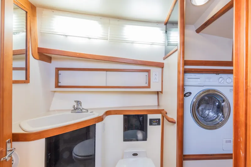 Slide: The Image of 2002 Sabreline 47 yacht bathroom with sink, washer, and wooden accents. - 12