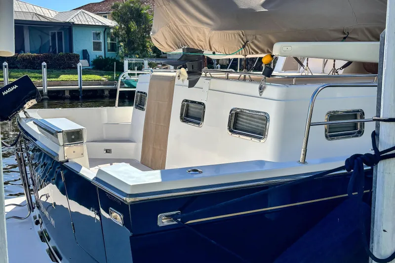 Slide: The Image of 2002 Sabreline 47 yacht docked, featuring a sleek blue hull and spacious deck area. - 17