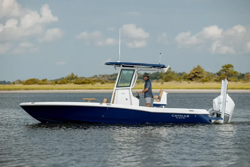 Slide: The Image of 2025 Caymas 26 HB boat on calm water with a person at the helm. - 2