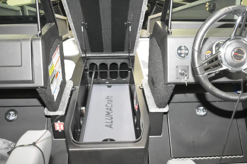 Slide: The Image of 2026 Alumacraft Competitor 195X Sport boat interior with storage compartment and steering wheel. - 10