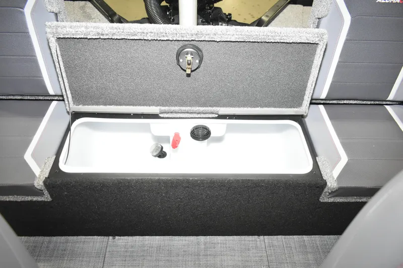 Slide: The Image of 2026 Alumacraft Competitor 195X Sport boat storage compartment with open lid and interior view. - 13