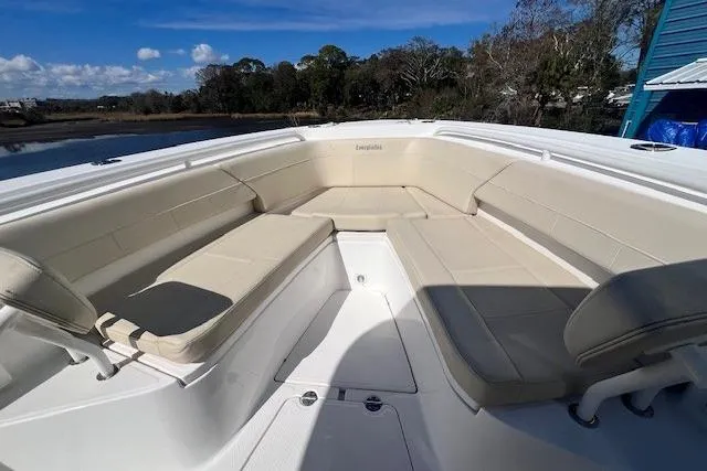 Slide: The Image of 2018 Everglades 335 Center Console boat with spacious seating area, docked by a scenic shoreline. - 15