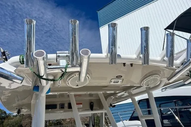 Slide: The Image of 2018 Everglades 335 Center Console boat with multiple rod holders, docked near a blue building. - 32