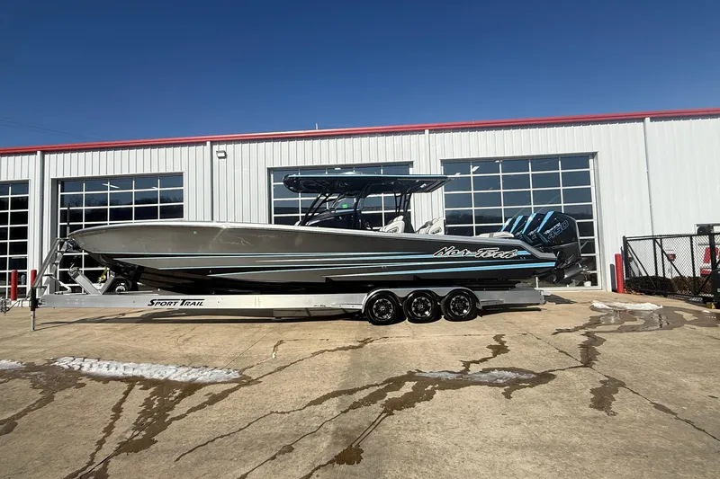 The Image of 2023 Nor-Tech 390 Sport Center Console boat on trailer outside a garage. - 1