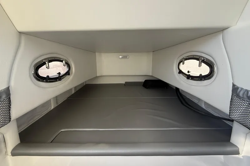 Slide: The Image of 2023 Nor-Tech 390 Sport Center Console cabin interior with portholes and cushioned seating. - 23