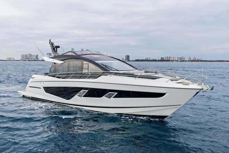 Slide: The Image of 2022 Sunseeker 65 Sport Yacht cruising on open water with city skyline backdrop. - 17