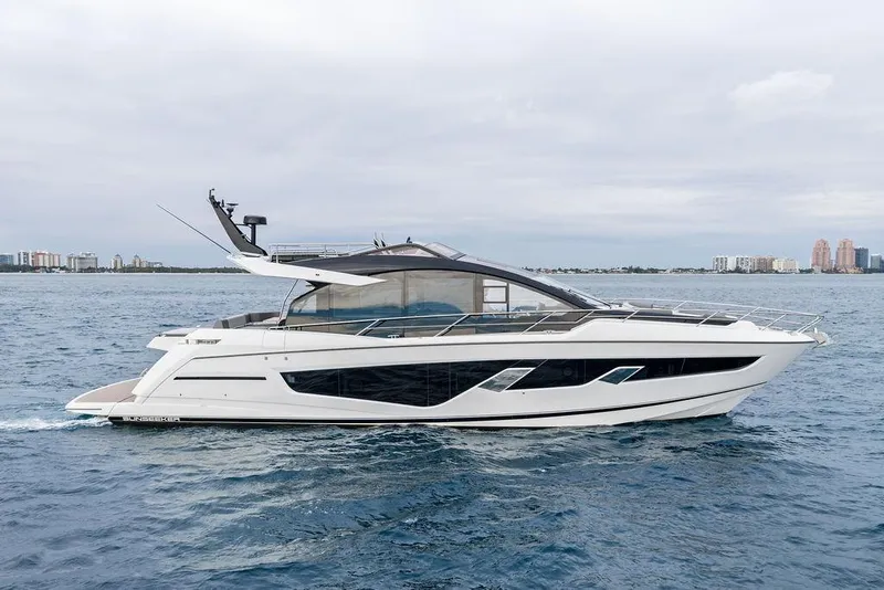 Slide: The Image of 2022 Sunseeker 65 Sport Yacht cruising on open water, city skyline in background. - 18