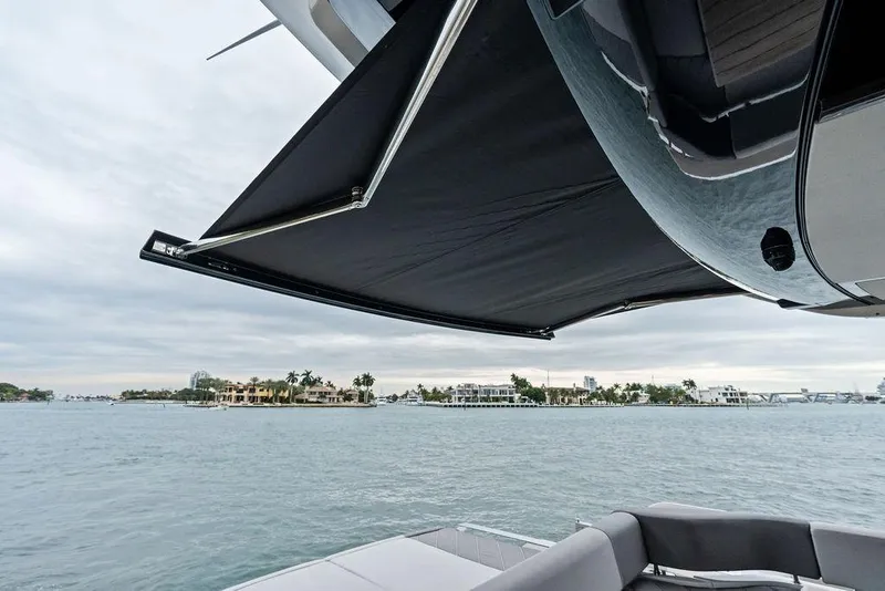 Slide: The Image of 2022 Sunseeker 65 Sport Yacht with extended awning, overlooking waterfront homes. - 58