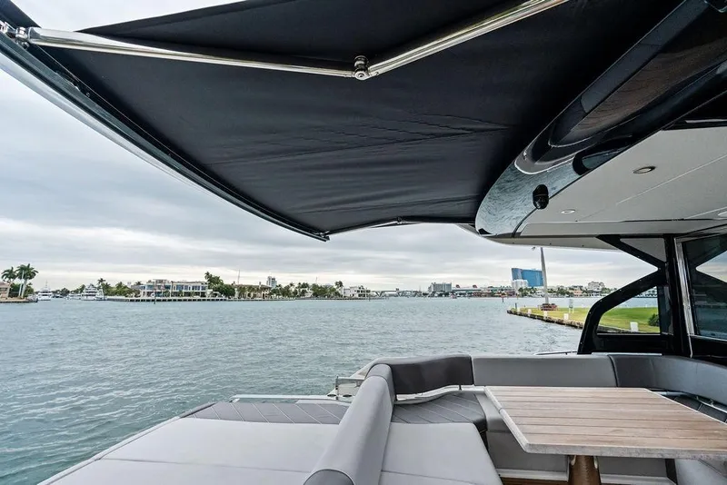 Slide: The Image of 2022 Sunseeker 65 Sport Yacht deck with awning, overlooking waterfront view. - 59