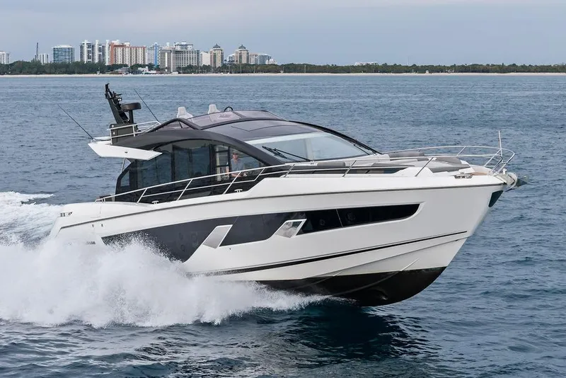 Slide: The Image of 2022 Sunseeker 65 Sport Yacht cruising on open water near a city skyline. - 6