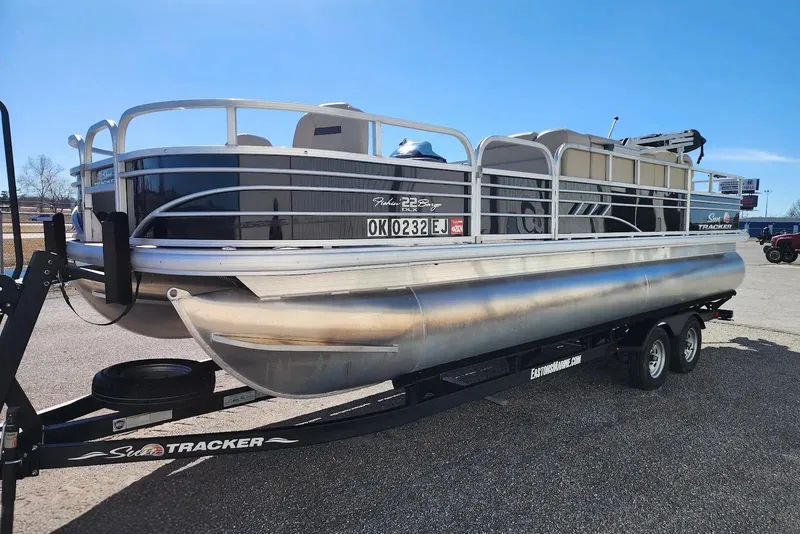 Slide: The Image of 2022 Sun Tracker Fishin' Barge 22 DLX pontoon boat on trailer, parked outdoors. - 10