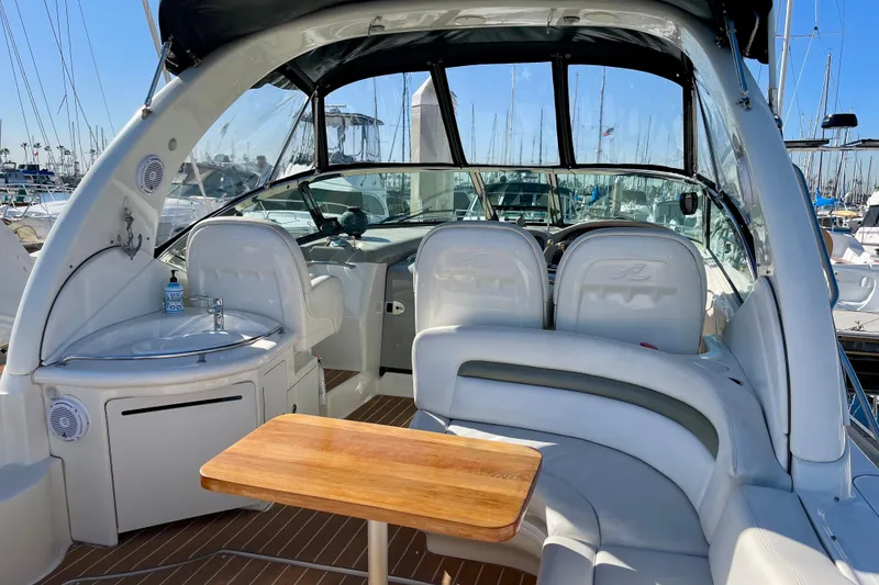 Slide: The Image of 2007 Sea Ray 340 Sundancer interior with seating, table, and helm in a marina setting. - 21