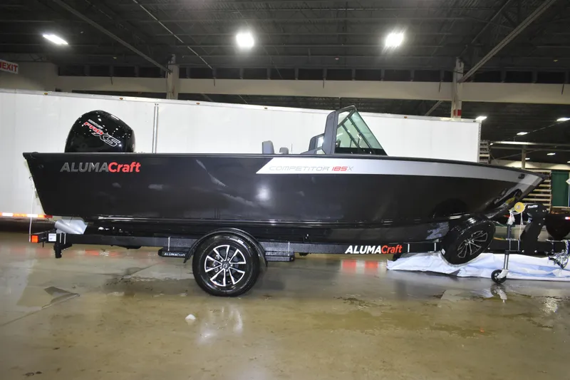Slide: The Image of 2026 Alumacraft Competitor 185X Sport boat on display indoors. - 1