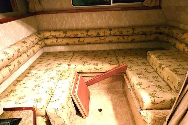 Slide: The Image of 1990 Sea Ray Sundancer 310 cabin interior with palm-patterned seating and storage access. - 13