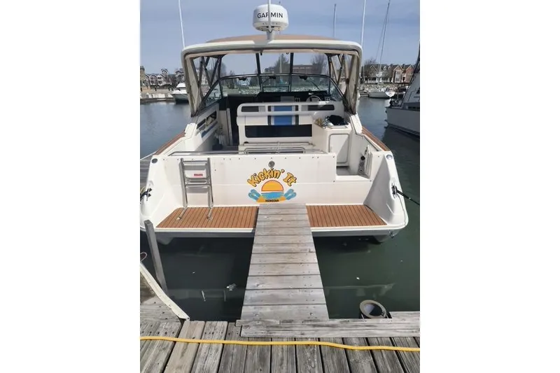 Slide: The Image of 1990 Sea Ray Sundancer 310 docked at marina, rear view with custom graphics. - 3