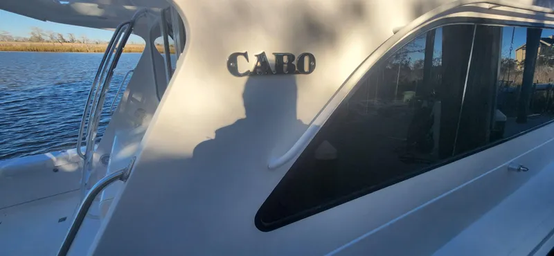 Slide: The Image of 2004 Cabo 48 Convertible yacht on calm water, side view with shadow. - 11