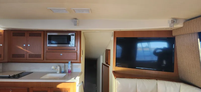Slide: The Image of Interior of 2004 Cabo 48 Convertible yacht with kitchen and TV area. - 14