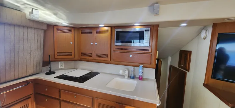 Slide: The Image of 2004 Cabo 48 Convertible yacht kitchen with wooden cabinets, microwave, and countertop. - 21