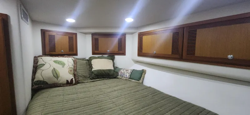 Slide: The Image of Cozy cabin interior of 2004 Cabo 48 Convertible with wood cabinets and patterned bedding. - 28