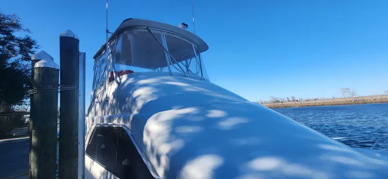 Slide: The Image of 2004 Cabo 48 Convertible yacht docked by a serene waterfront. - 3