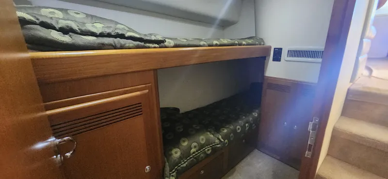 Slide: The Image of 2004 Cabo 48 Convertible yacht interior with wooden bunk beds and patterned bedding. - 30