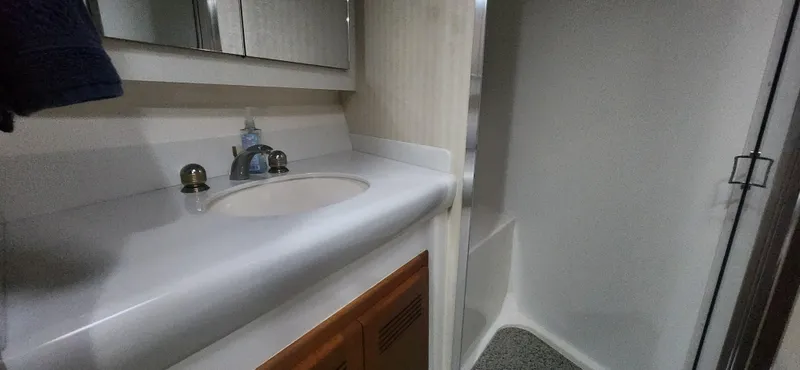 Slide: The Image of 2004 Cabo 48 Convertible bathroom with sink, mirror, and shower area. - 32