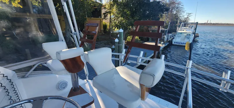 Slide: The Image of 2004 Cabo 48 Convertible yacht with seating, docked by a scenic waterfront. - 9