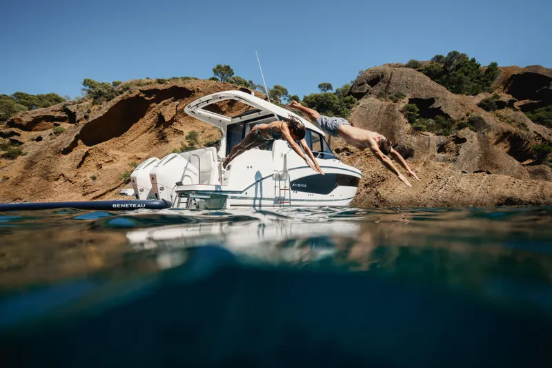 Slide: The Image of 2027 Beneteau Antares 9 V2 with people diving into clear water near rocky cliffs. - 12