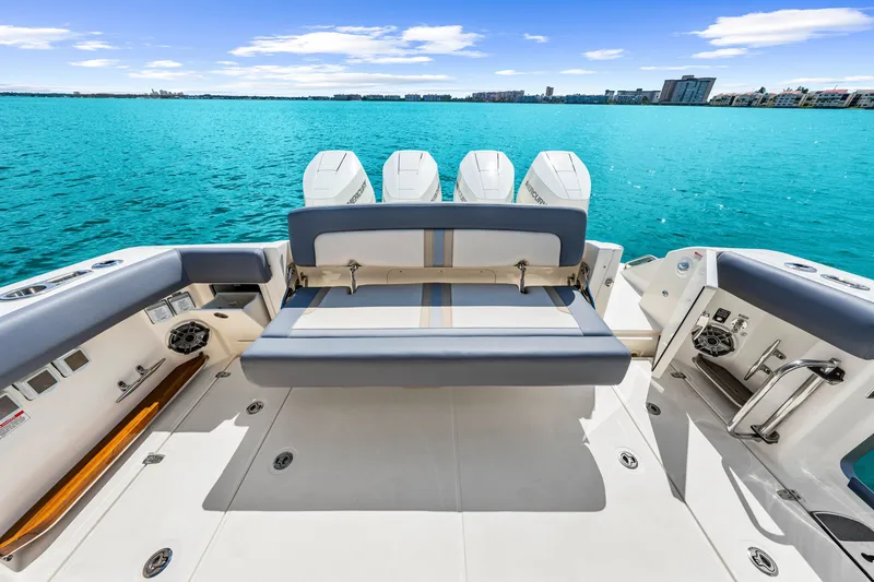 Slide: The Image of The image shows the stern of a Boston Whaler 380 Realm with four engines and a bench seat. - 44