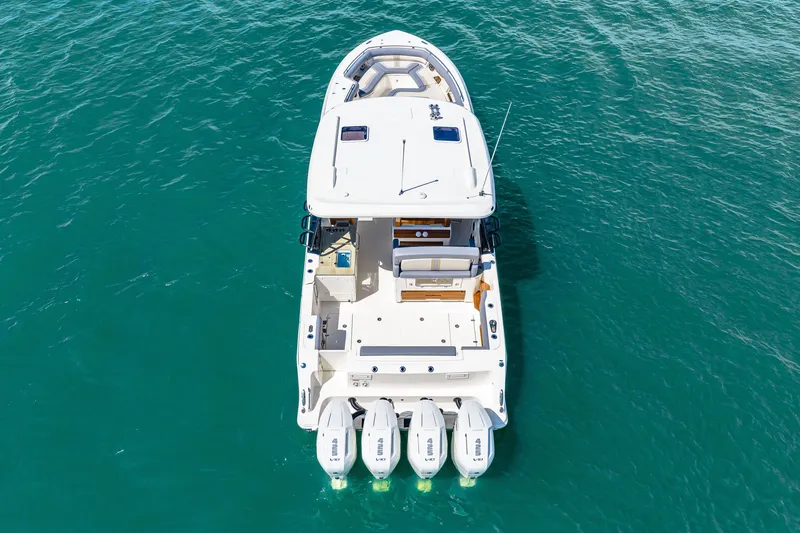 Slide: The Image of The 2026 Boston Whaler 380 Realm is a sleek boat with four outboard engines on calm water. - 6