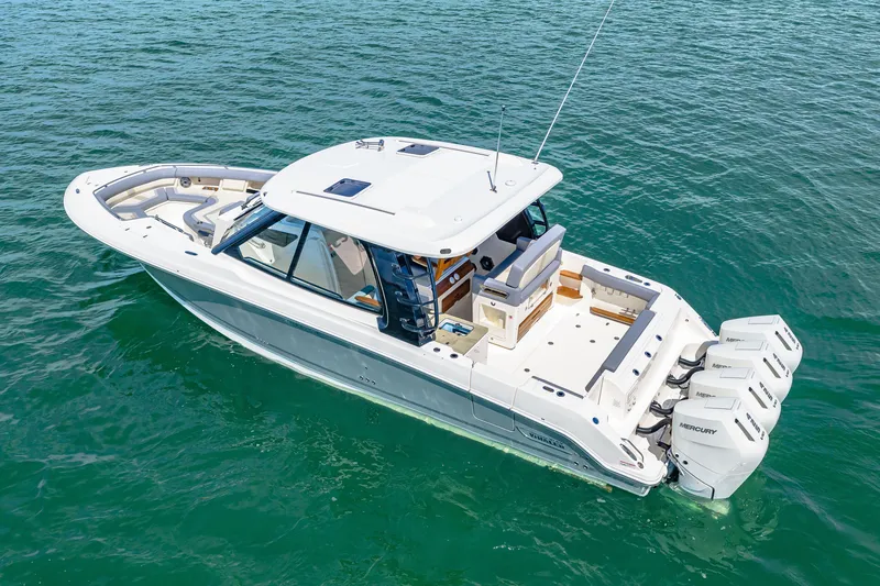 Slide: The Image of A 2026 Boston Whaler 380 Realm on calm water. It features a spacious deck and three outboard engines. - 9