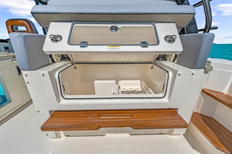 Slide: The Image of Boston Whaler 380 Realm 2026: Storage compartment with wooden accents and seating. - 48