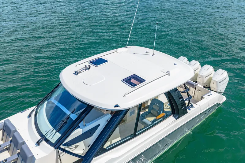 Slide: The Image of The image shows a Boston Whaler 380 Realm boat on calm water with four outboard engines. - 13