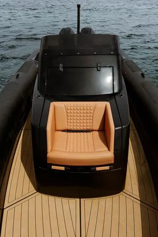 Slide: The Image of 2022 Roughneck RIB 1010 boat with tan seating and sleek black design on water. - 13