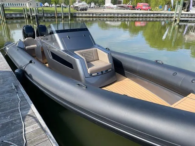 Slide: The Image of 2022 Roughneck RIB 1010 boat docked, featuring sleek design and dual engines. - 5