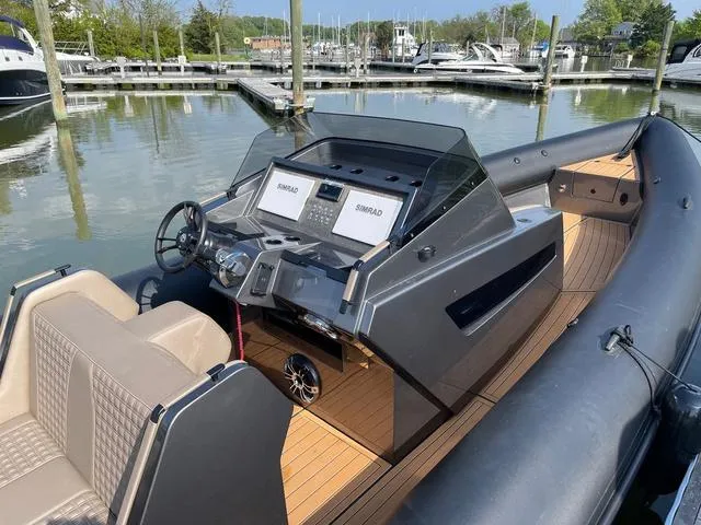 Slide: The Image of 2022 Roughneck RIB 1010 boat with modern dashboard and seating at a marina. - 7