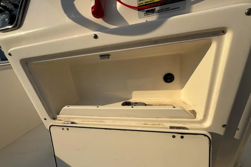 Slide: The Image of 2015 Cobia 201 Center Console storage compartment with open hatch and visible switch. - 16