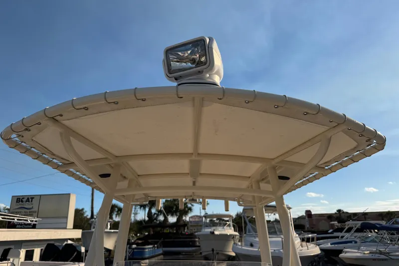 Slide: The Image of 2015 Cobia 201 Center Console boat with T-top and spotlight, under clear blue sky. - 24
