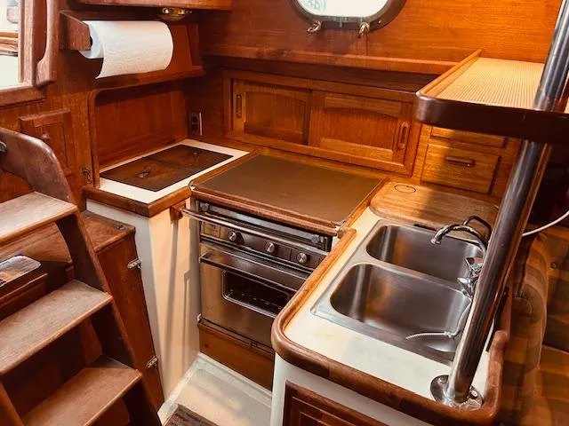 Slide: The Image of 1986 Pacific Seacraft 34 yacht kitchen with stove, sink, and wooden cabinetry. - 12