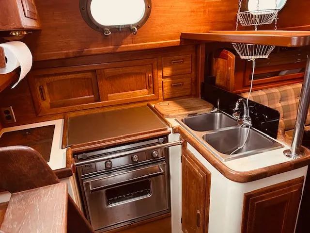 Slide: The Image of 1986 Pacific Seacraft 34 yacht kitchen with wood cabinetry, dual sinks, and stove. - 13