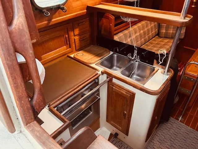 Slide: The Image of 1986 Pacific Seacraft 34 yacht interior with wooden cabinetry and dual sink kitchen area. - 14