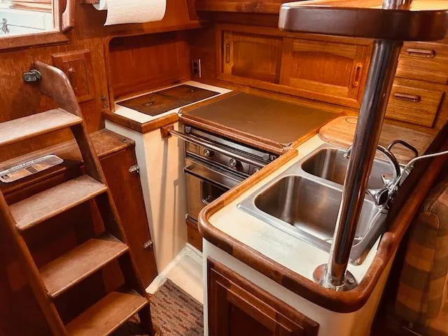 Slide: The Image of 1986 Pacific Seacraft 34 yacht galley with wooden cabinetry, stove, and sink. - 15