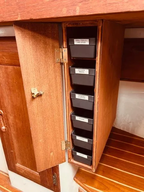 Slide: The Image of Wooden cabinet with labeled storage bins inside a 1986 Pacific Seacraft 34 sailboat. - 17