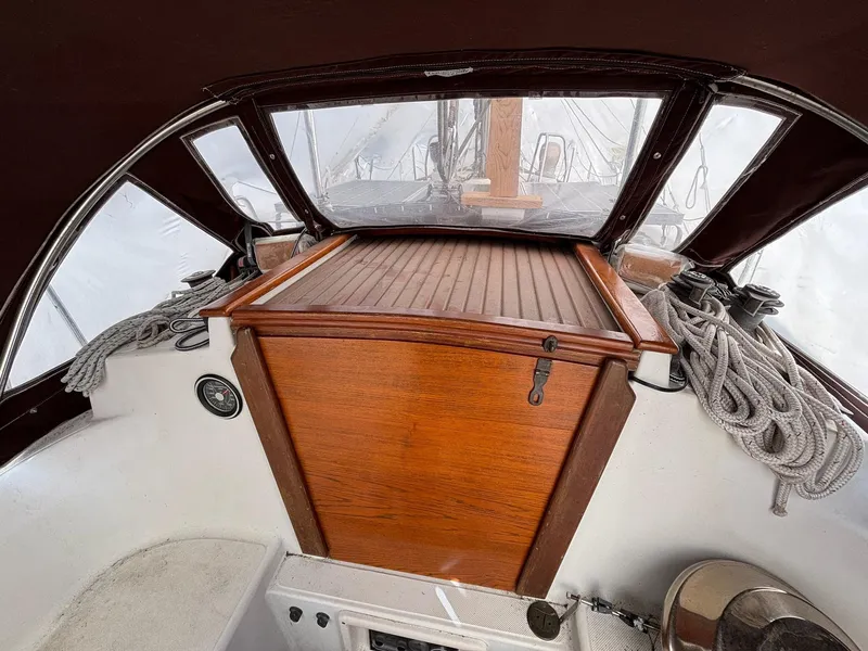 Slide: The Image of 1986 Pacific Seacraft 34 sailboat cockpit with wooden hatch and coiled ropes. - 20