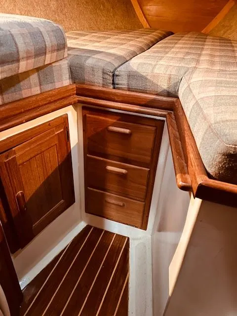 Slide: The Image of 1986 Pacific Seacraft 34 interior with plaid cushions, wooden drawers, and cabinet. - 9