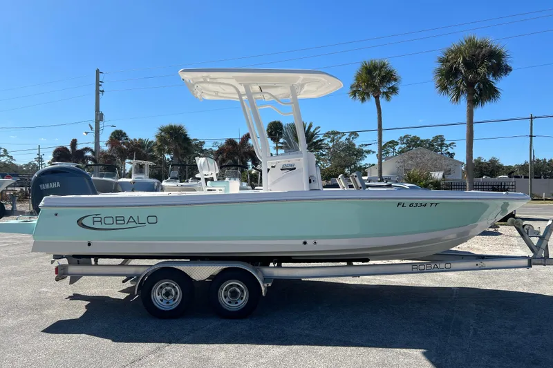 Slide: The Image of 2024 Robalo 226 Cayman boat on trailer, parked outdoors under clear blue sky. - 4
